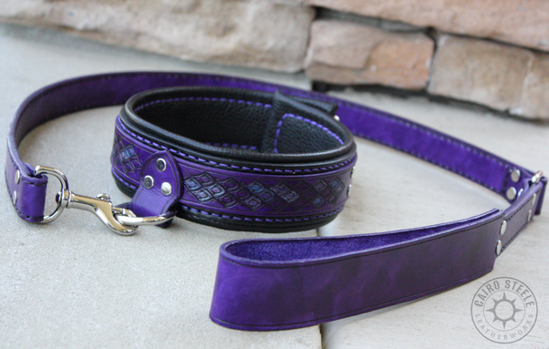A handmade leather collar and leash. The collar has a purple top strap with dragonscale stamping and metallic silver accent scales, over a black base strap and liner. It has purple stitching and nickel plated brass hardware. The leash is solid purple with black stitching.