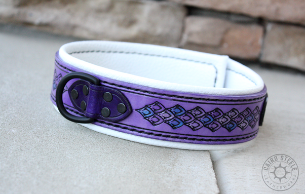A handmade leather collar. It has a lilac base strap with dragonscale stamping and metallic silver and blue accent scales. The liner is white, with black stitching. The top straps are dark purple and the hardware is black.