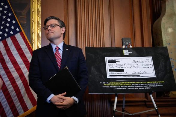 Speaker Mike Johnson in 2023 posing with an enlarged photo of a $40K check made out to former VP Joe Biden in 2017 by his daughter-in-law, claiming it was actually a "laundered Chinese bribe."