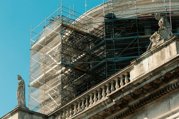 scaffolding next to statues at the top of a building