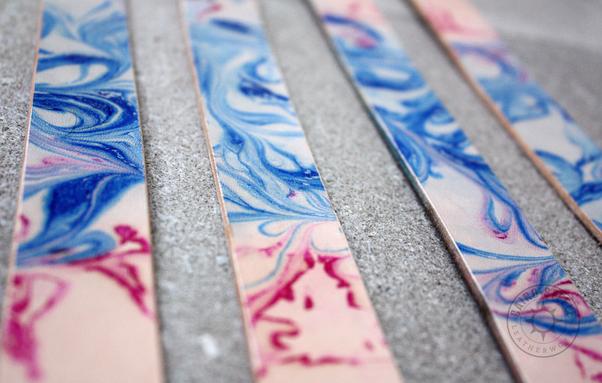 A close up of several trans flag marbled collar straps