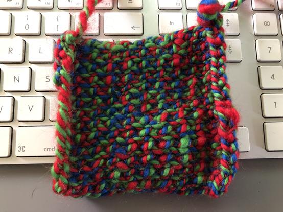 A knitted swatch of red green and blue yarn