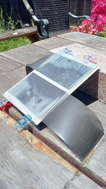 two negatives clamped to cyanotype paper between rectangles of plywood and plexiglass