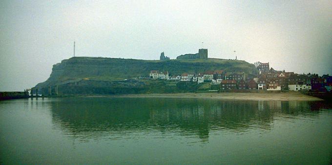 A hill, with a ruined abbey on top, reflected by the sea.