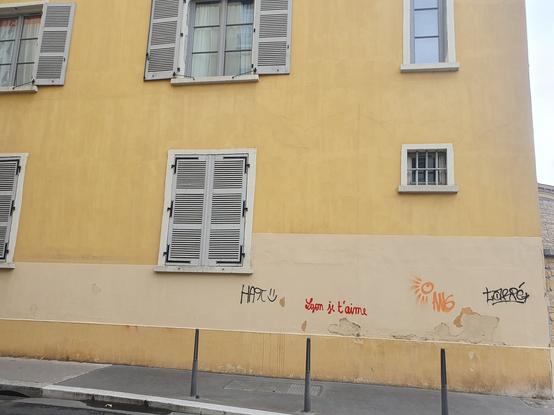 a yellow building with a "Lyon je t'aime" graffit'ed on a corner