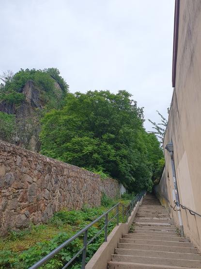 a stair climbing up Fourvière between 2 walls. behind left wall,some trees and a big rocky outcrop