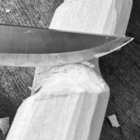 A knife resting on a rough cut in wood.