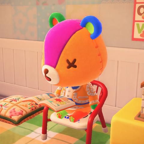 Animal Crossing: New Horizons screenshot showing Stitches (patchwork, multi-colored bear cub with X's for eyes that look to be stitched on) is sitting in a red baby chair in his home reading a comic book with very colorful pages.
