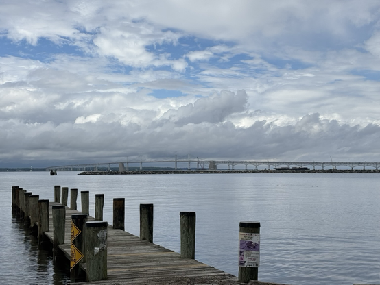 Looking out over a pier with the Chesapeake Bay Bridge in the distance. Dramatic thunder clouds forming. With blue skies peaking through