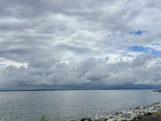 Dramatic sky  filled with thick, layered clouds, but there’s a hint of brighter weather in the upper right quadrant, where patches of blue sky peek through.