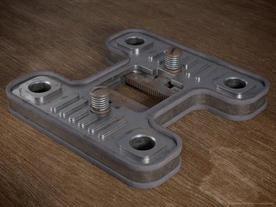 Flat H shaped metallic plate with a Rubberised rim and a central clamping system held in place with 2 sprung screws.