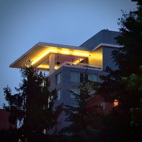 The top corner of a city skyrise building is pictured against a grainy, early-morning twilight sky.