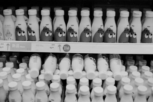 Lucky SHD 400

**English Alt Text:**
"Black and white photograph of shelves in a store stocked with numerous bottles of milk. The bottles are arranged in rows, with some bottles having caps and others without. The shelves are labeled with signs indicating new products."

**Chinese Alt Text:**
"黑白照片展示了商店货架上摆满的牛奶瓶。瓶子整齐排列，有些有盖子，有些没有。货架上有标志表明是新产品。"