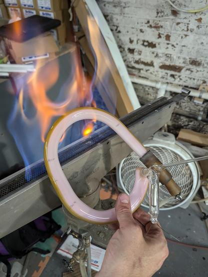 holding the Horsey Marcheschi glass horseshow during production over the ribboin burner bushy, "puffy" flame, latex rubber hose adaptors and blowhose still attached to the glass handle I used to bend the previous curve.