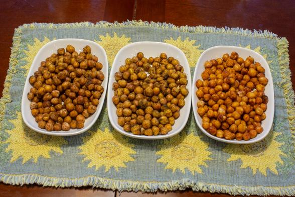 Three oblong white plates piled with dark, spice-covered garbanzos, all resting atop a woven, sunflower-themed placemat. The aroma is indescribably good.