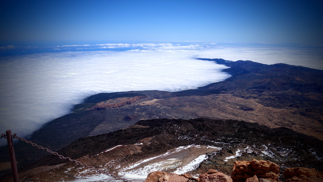 Auf dem Teide Vulkan fast 4000m hoch. 2000m darunter eine karge Hochebene. Rund rum weiße Wolken, so dass man den grünen Teil der Insel weiter unten nicht sehen kann. Auch das Meer ganz unten ist nur zu erahnen. Unter Wasser bis zum Meeresgrund ist es weit. Insgesamt ist man daher mehr als 7000m über der Erdoberfläche. Da in der Umgebung sonst nichts ist außer ameisengroße Schiffchen, spatzengroße Passagiermaschinen im Anflug und sehr viel Weite, fühlt es sich besonders an...