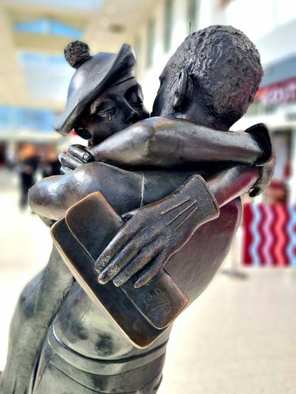 A bronze statue of a young couple in a close embrace.
