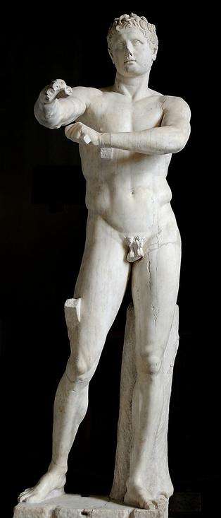 Photo: Marie-Lan Nguyen/ Wikimedia

The image shows a marble statue of a young, muscular male figure. The statue is nude and is shown in a contrapposto stance, with one leg bearing more weight than the other. The statue's right arm is outstretched, in the left hand is a strigilis with which the figure is lowering the right arm. The backdrop is plain black, focusing attention solely on the statue.