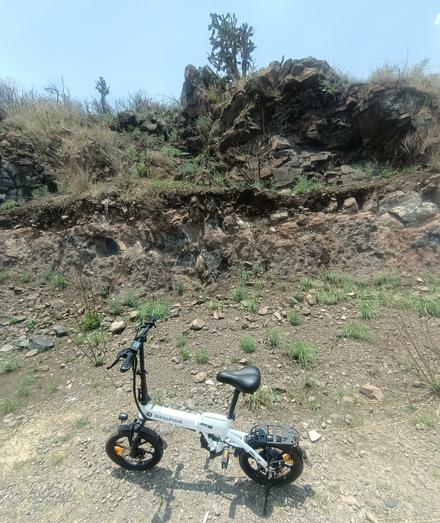 another photo of my small ebike parked in front of a rock and some cactus