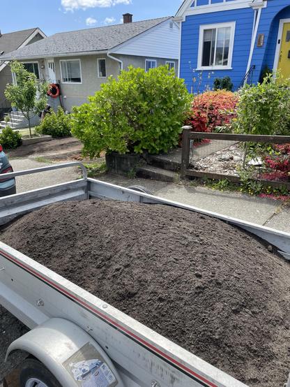 A small trailer is filled to the brim with dark soil that has quite a bit of sand in it for improved drainage. We need that around here when everything is Clay heart pan.