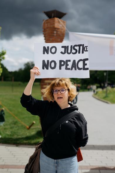 A student is standing with a placard saying "No justice, no peace".