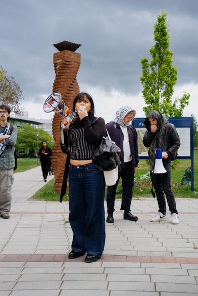 A student protester on megaphone, and we can see two students behind trying to see if another megaphone is working or not.