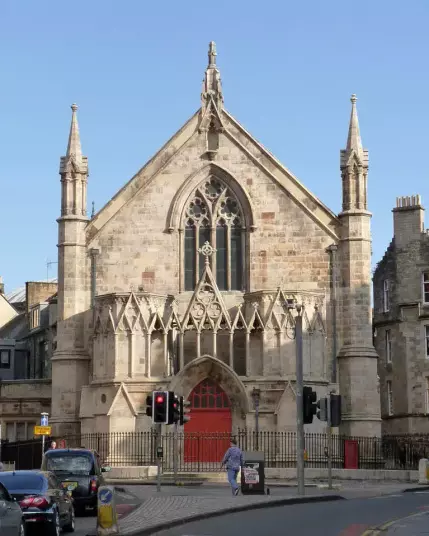 The image depicts a church or similar building characterized by its architectural features, including pointed arches, decorative stonework, and spires. The facade showcases intricate details typical of Gothic-style architecture. There are also traffic signals and a street scene in front of the building, indicating it is situated in an urban area.

Image Credits: Wikimedia / Alan Murray-Rust  / CC BY-SA 2.0