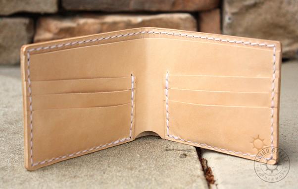 The interior of the wallet, which is entirely undyed leather with white stitching and a makers mark in the bottom right corner. It has 6 card slots and a billfold.