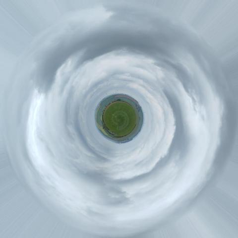 A photograph of some green hills and fields in the countryside below a cloudy sky, but turned into a tiny planet. Because the source photo was mostly sky, the planet's radius is only ~1/8th of the width of the image, leaving the clouds above to swirl around it.

The edges of the images copy the outermost pixel outwards, creating subtle streaks outwards to frame the image.