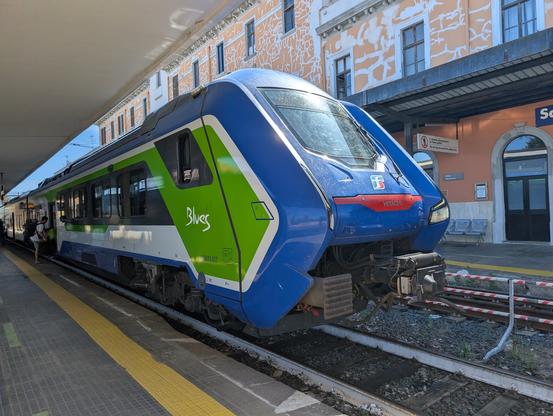 A blue, white and green train at a station