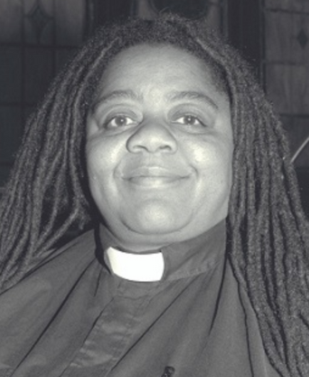 Gwen Hall, a smiling Black woman with long dreads, wearing a clerical collar