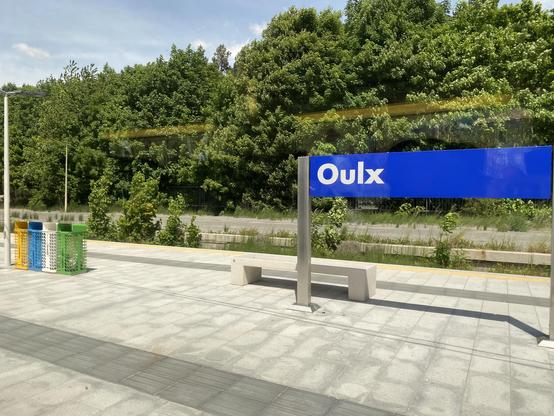 A train station name board reading “Oulx” in white lettering on blue.