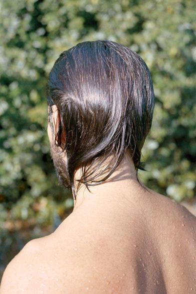 #5, excerpt from the series Regrets by Stefano Marchionini, c. 2018 and ongoing (photography) is an outdoor photograph of a young man's back in the sunlight with water droplets on his skin, hair sleek and wet.