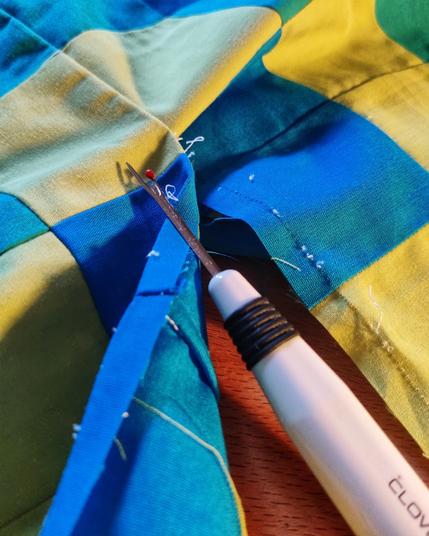 Unpicker tool midway through fabric seams.