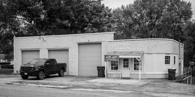 Black and white image of an old car repair shop and/or gas station turned into a gym.