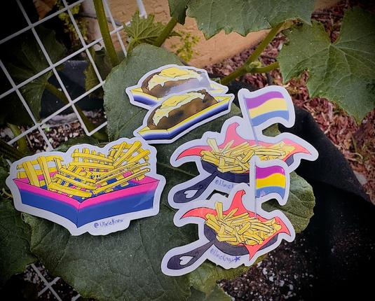 using a cucumber leaf as artistic display, three types of stickers are displayed. bi-pride, pan-pride, and nonbinary-pride.