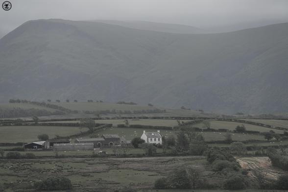 White farm house and buildings against mountain backdrop