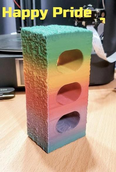 A rainbow spray painted brick with the heading "happy pride".