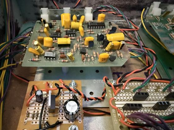 Three circuit boards of different sizes and filled with all kinds of different electronic components, most of them yellow. Multicolored wires flow from the edges.