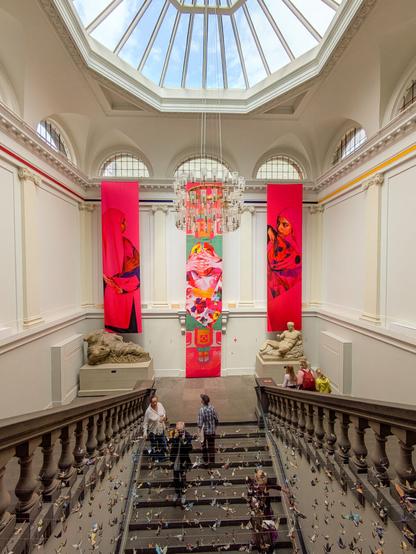 Three large silken banners in bright magenta hues hang from a large stairway