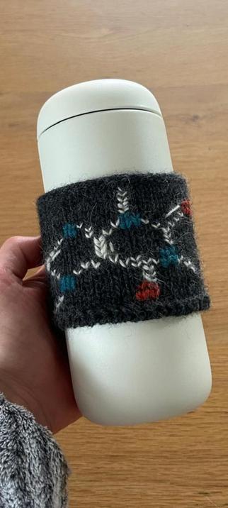 Coffee cup sleeve, knitted in black, with embroidered coffee molecule on it