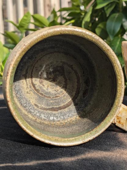 Inside the mug, a darker green swirl on the bottom signifies it is a wheel-thrown form.