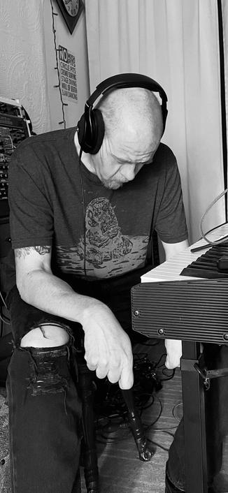 A black and white photo of a rather craggy looking man listening intently to playback while producing.