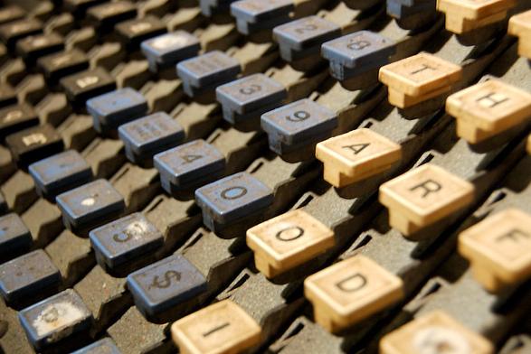 A view of the square plastic keys  from a linotype machine seen from one side showing the numerals and the capital letters in the foreground