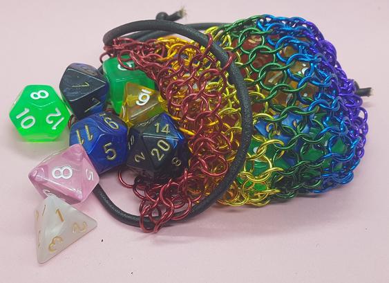 A dice bag made from chainmail, in rainbow colours.
Assorted dice spill out from the left side.