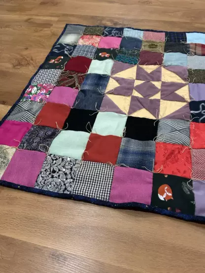 An angled view of the blanket on the floor. You can see that there are sparkly fabrics and brocades and inherently textured and soft and flannel and pretty ones with embroidery