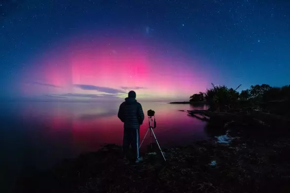 A photographer captures the aurora australis – or southern lights – glowing on the horizon over Lake Ellesmere in New Zealand.