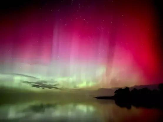 Green & red aurora covering all sky reflecting in the lake.