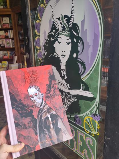 Le roman graphic "LE DERNIER JOUR DE HOWARD PHILIPS LOVECRAFT" tenu devant la porte d'entrée de la Librairie Chimères.