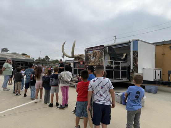 Students lined up in front of the Mobile Museum trailer getting instructions for their activities.